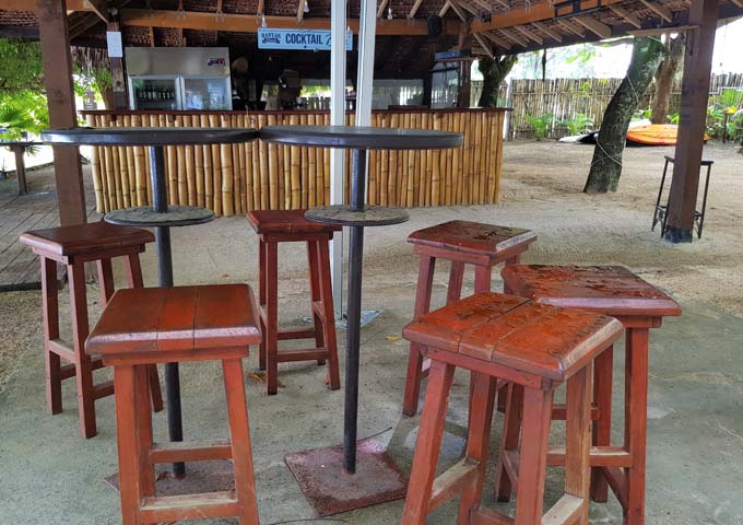 The open-air bar is tropical with sand and wood.
