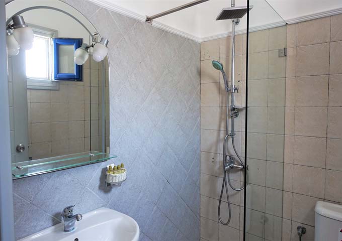The small bathroom has a dated glass shower and podium sink.