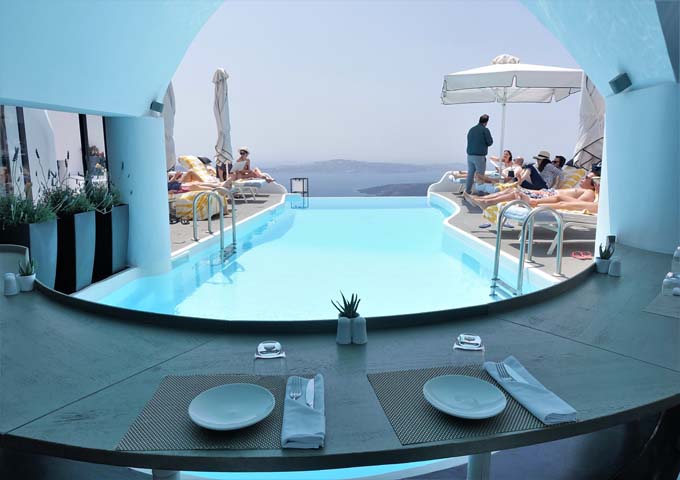 The infinity pool is surrounded by the restaurant and sun loungers.