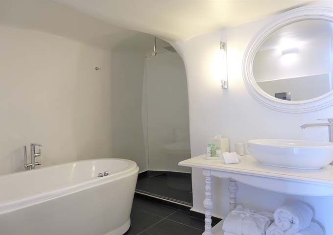 The spacious cave-style bathroom has an open shower and a jacuzzi bathtub.