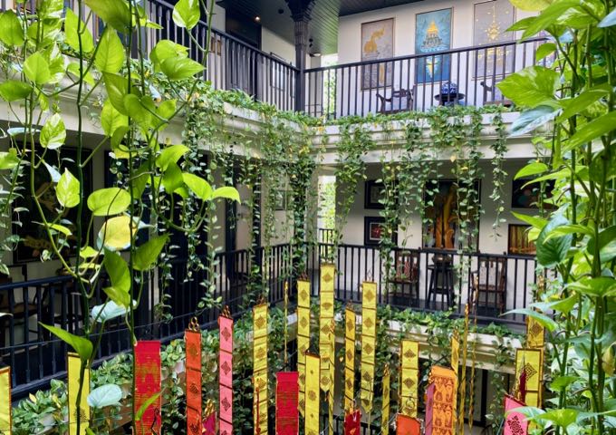 Elegant Thai hotel courtyard with hanging plants and colorful banners
