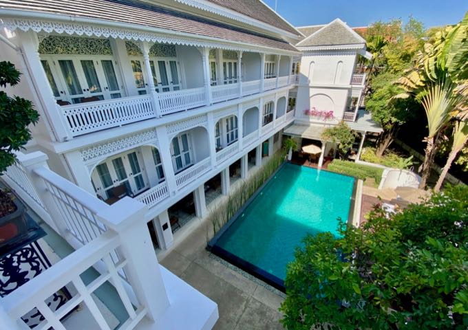 White, Thai-style hotel with wraparound veranda overlooking a small swimming pool