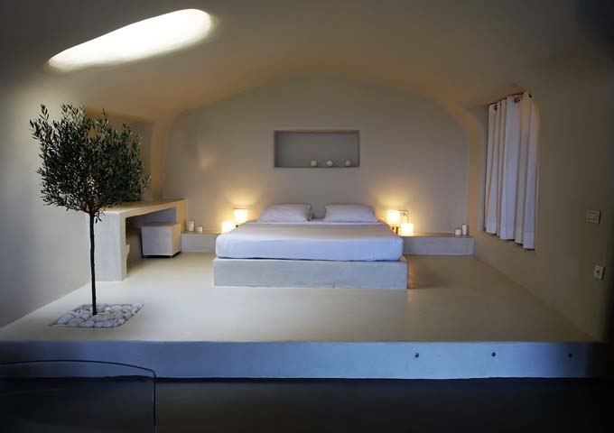 The cave-style main bedroom features a king bed, olive tree and skylight.