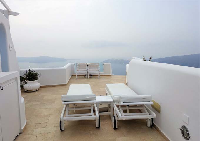 The large terrace features an al fresco dining table, sun loungers, and fantastic caldera views.