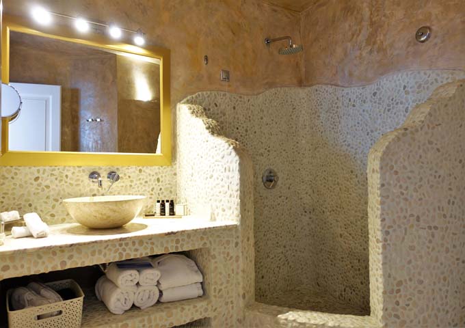 The bathroom has a large shower and natural rock sink.