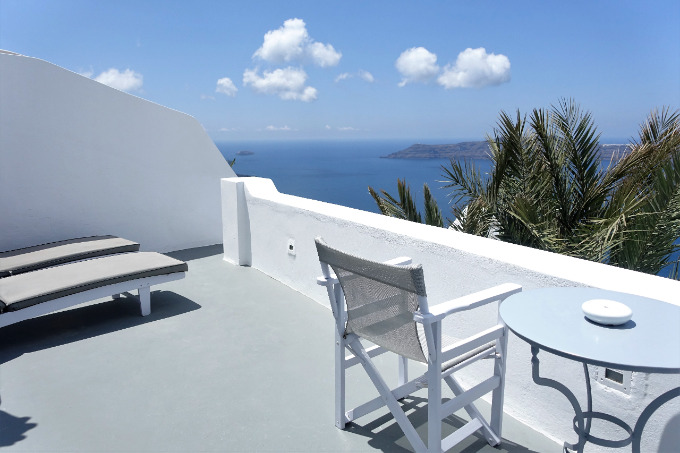 The room's private balcony has a small dining table and sun loungers.
