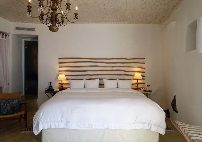 The bedroom has a king bed, exposed lava rocks, and concrete furnishing.