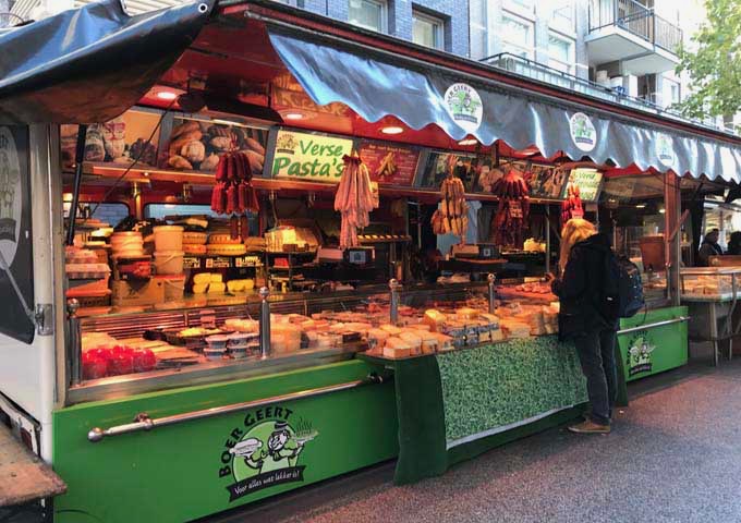 Ten Katemarkt features stalls selling cheeses, cold cutes, bread, fresh produce, and food.