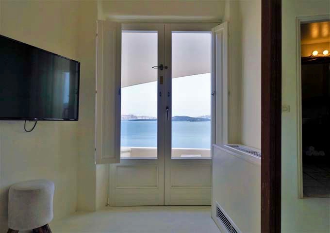 The bed offers caldera views through the French doors.