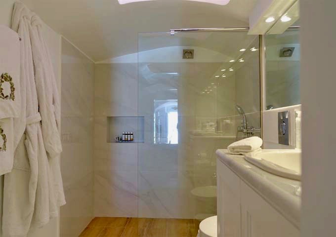 The suite's modern bathroom has a half-glass shower and luxury amenities.