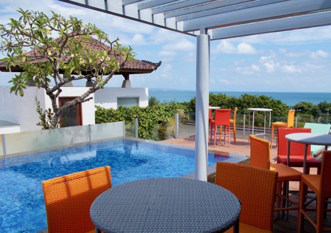 The rooftop pool is surrounded by colorful furniture.