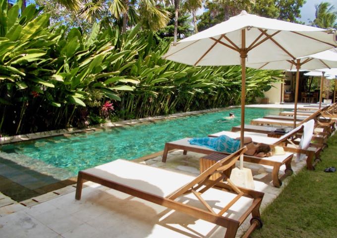 The pool has several lounge chairs with umbrellas.