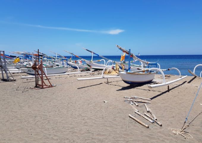 The sandy beach along the resort is lined with fishing boats.