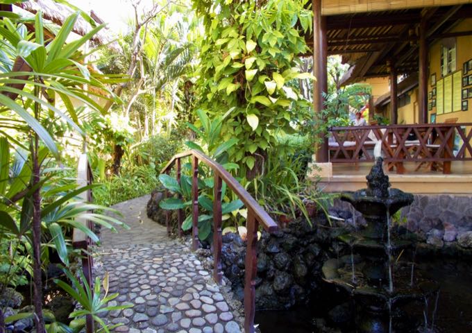 Bungalows are surrounded by lush gardens with stone paths and fish ponds.