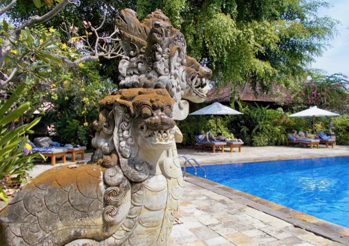 Traditional sculptures surround the shaded swimming pool.