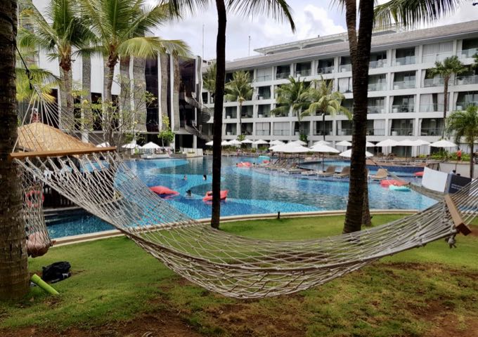 The large pool is surrounded by palms and hammocks.