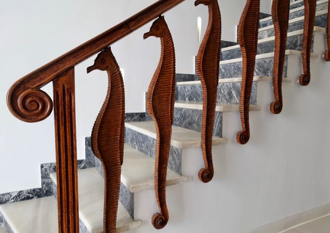 A staircase with a hand-carved seahorse bannister and marble steps is by the reception.