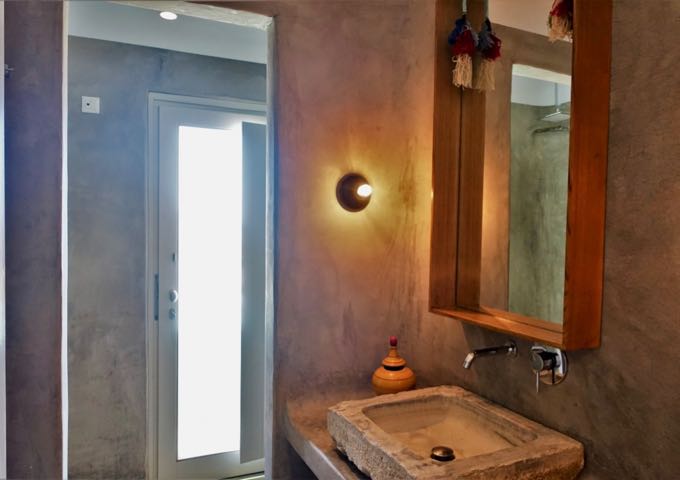 The suite's bathroom has pressed concrete, open shower with a window, and an antique sink.