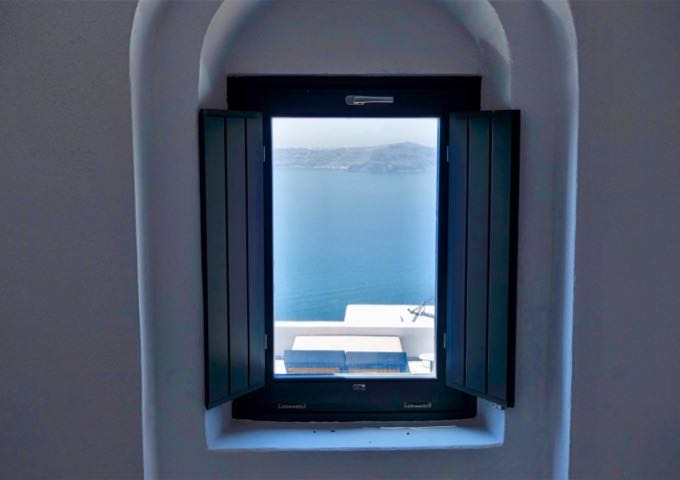 The loft windows offer views of the suite's terrace, caldera, and Thirassia Island.