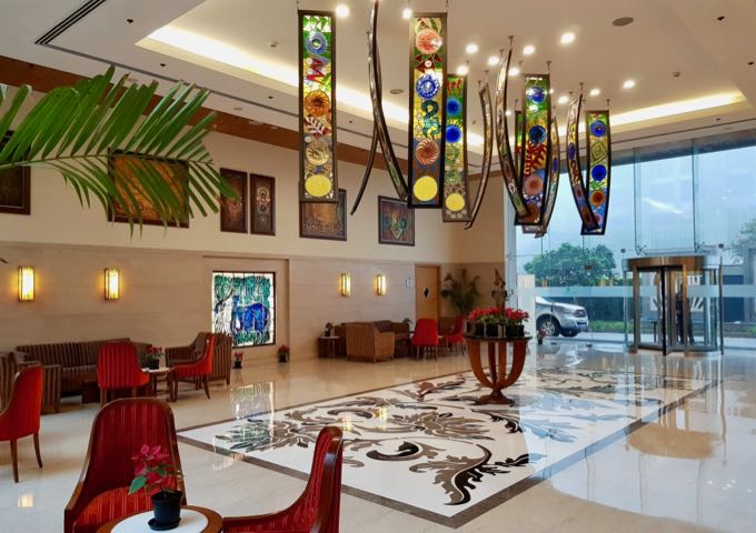The attractive lobby has colorful lampshades, contemporary art, and marble flooring.