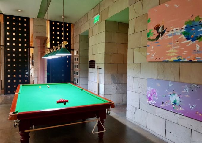 A snooker table is placed by the steps leading to the pool.