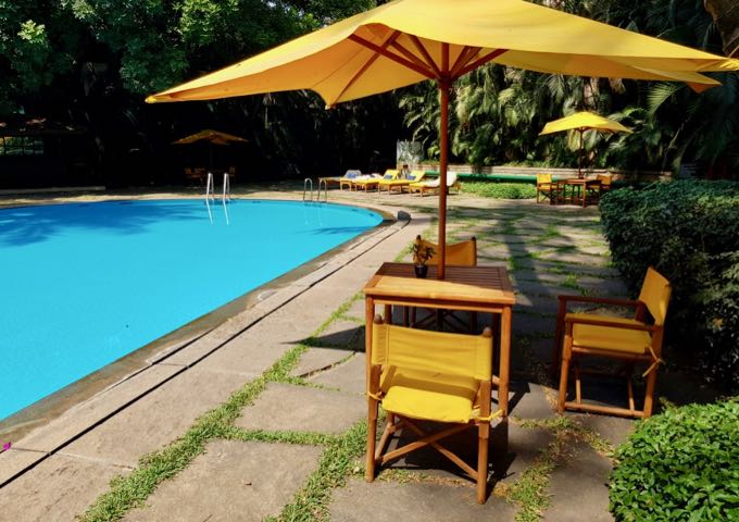 The tropical island-style pool features colorful chairs and umbrellas.