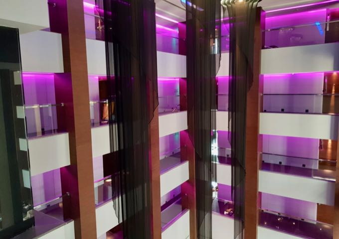 Corridors with magenta hues lead to the rooms around the atrium.