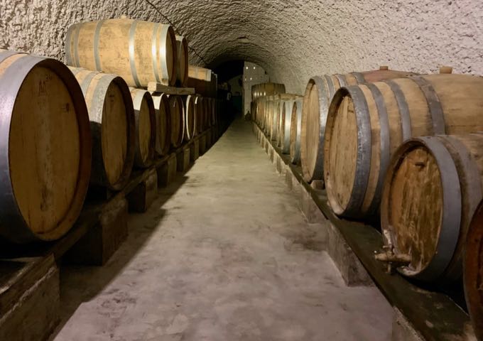 Rows of wine barrels in the Art Space Santorini winery barrel room.