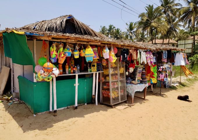 A few stalls sell souvenirs and beach gear on the sand.