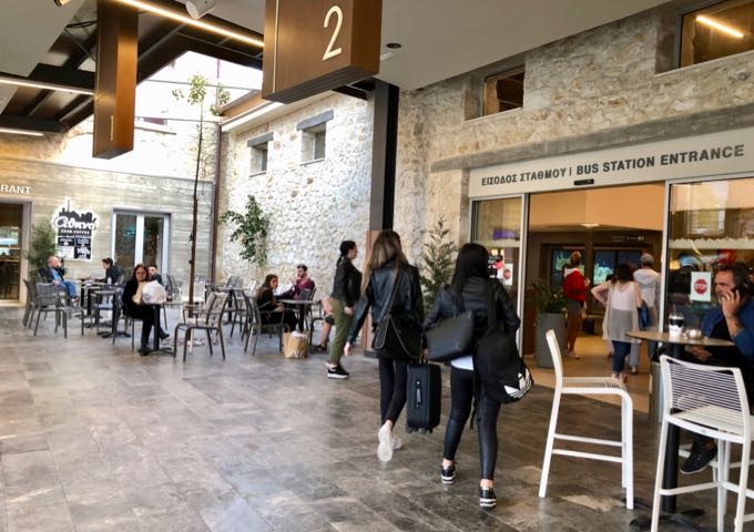 Travelers with suitcases entering the Heraklion bus station building.