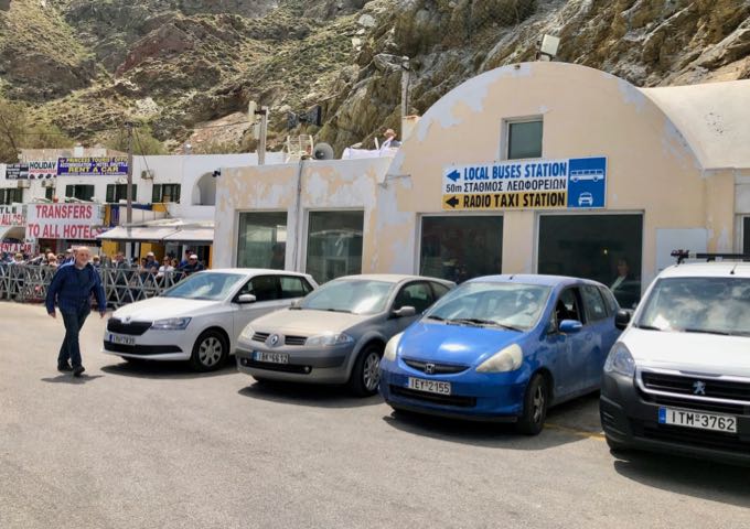 A sign pointing to Santorini local buses and taxis at Athinios ferry port