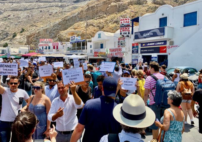 A group of drivers holding identifying signs in Athinios Port, Santorini