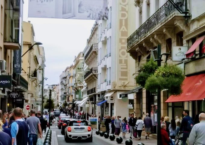 Rue d’Antibes is busy with people and boutiques.