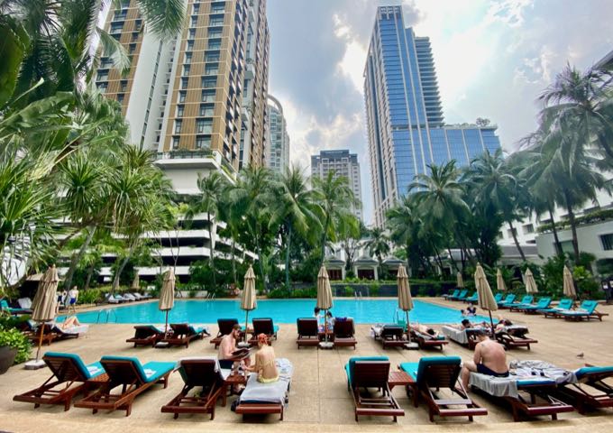 Hotel swimming pool surrounded by palm trees and skyscraper buildings