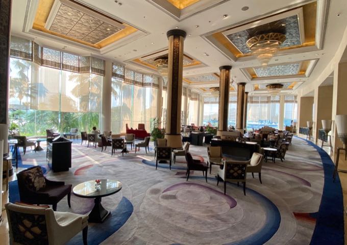 Elegant hotel lobby with plush velvet chairs, gold pillars, and floor-to-ceiling windows
