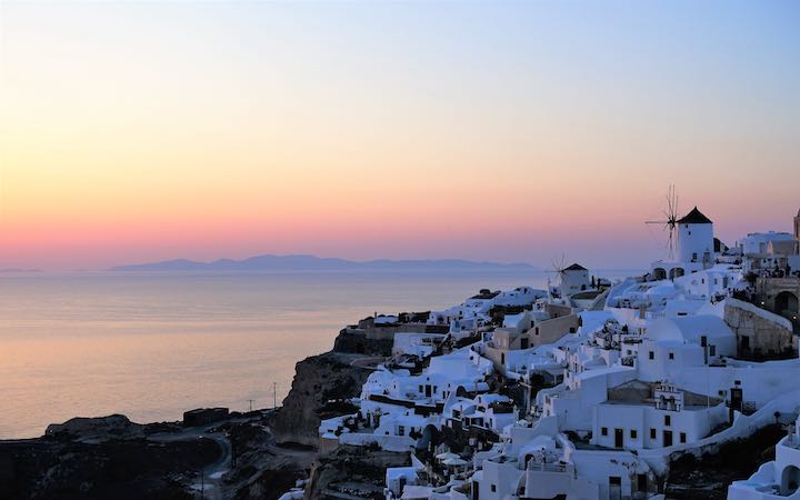 The famous Santorini sunset with windmills as seen from the Oia castle ruins