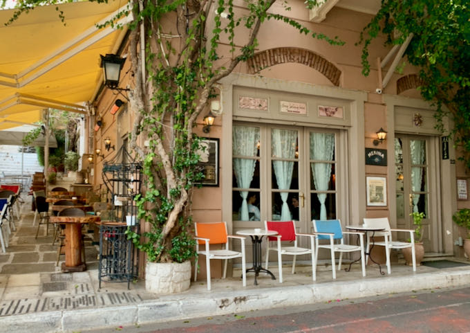 Exterior view of a restaurant with large, draped windows and cafe tables out front