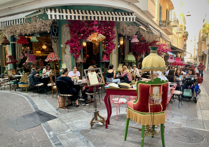 Cafe sidewalk chock-full of tables, frilly lamps and vases, and colorful decorations