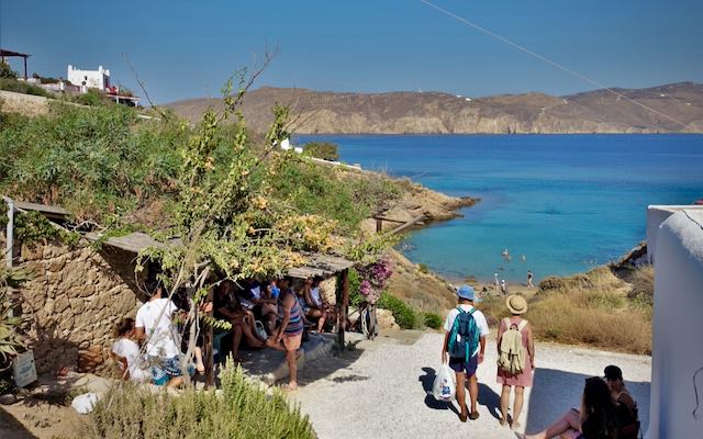 Travelers walking to a beachfront taverna in Greece
