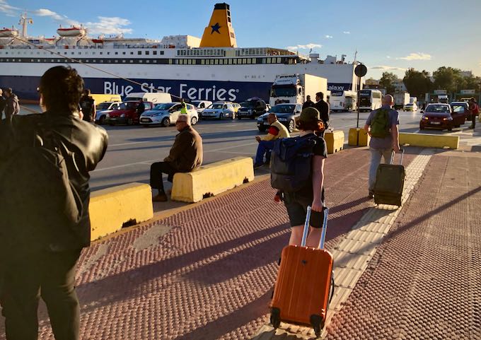 Travelers tow suitcases on their way to board a ferry