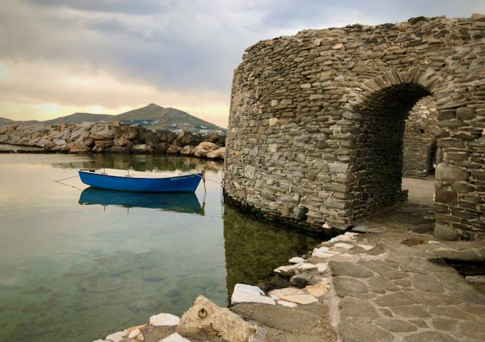 A blue fishing boat is tethered to a stone castle