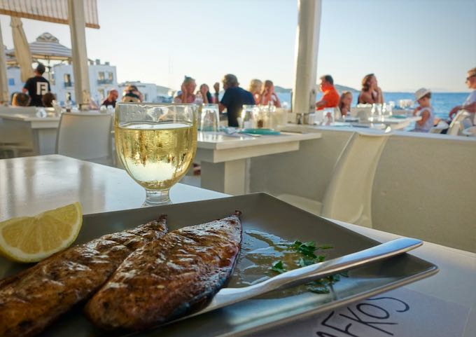 Grilled fish and white wine at a waterfront restaurant table