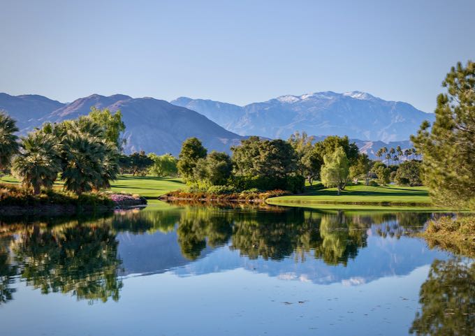 Pond on a green golf course, reflecting a mountain backdrop