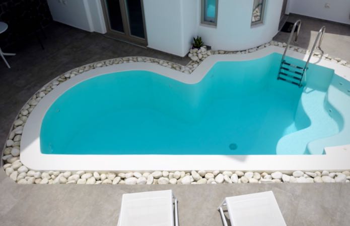 A small swimming pool with two sun loungers on an outdoor patio