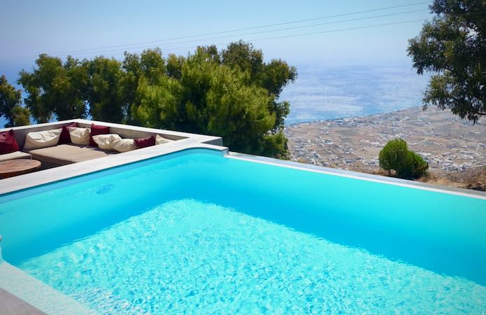 A hilltop infinity pool with an adjacent lounging area