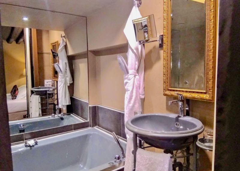 The bathroom has a bathtub and an ornate mirror.