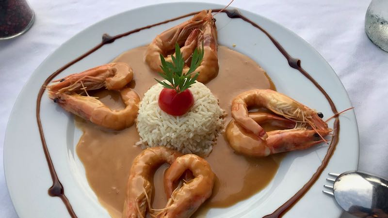 eight prawns artfully arranged on a plate in ouzo sauce