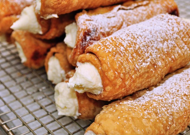 Cream-filled cannoli, stacked and ready to be sold