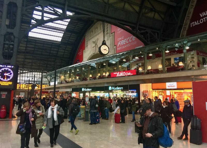 Travelers browse shops and services at the Milan train station