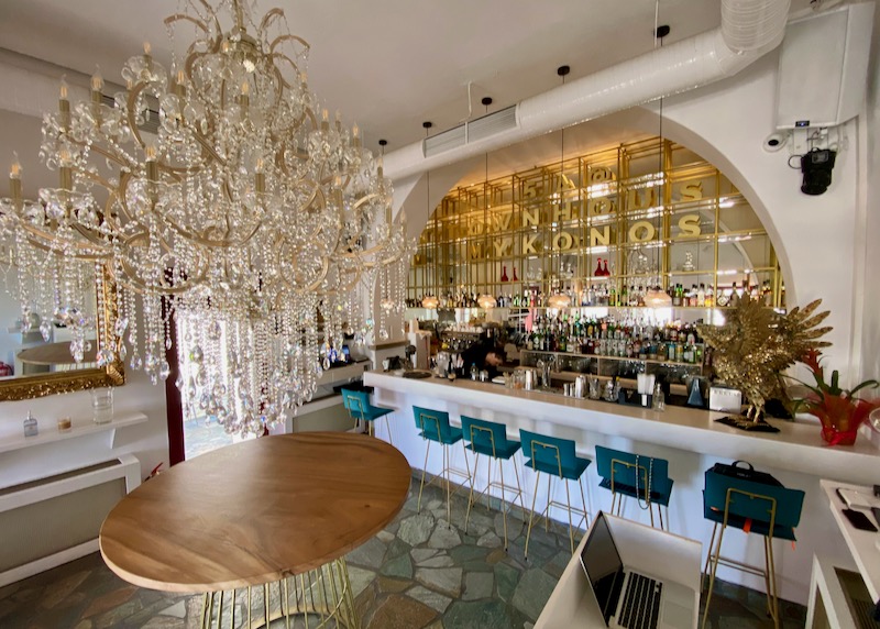 Gold-decked bar with turquoise barstools and an elegant chandelier 